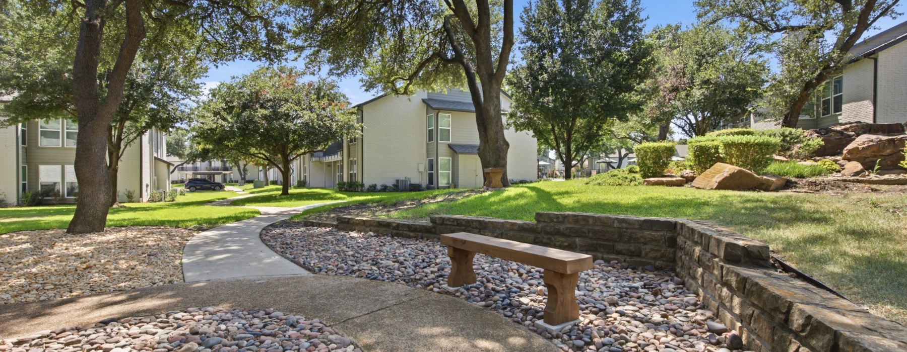 Scenic outdoor park area with stone pathway, bridge, and lush trees near Communities of Bent Tree