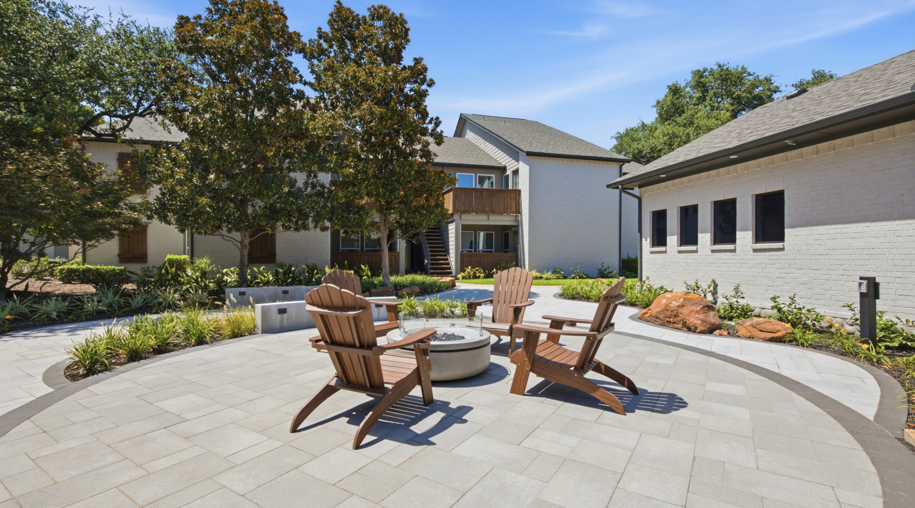 Outdoor courtyard with lounge seating around a fire pit surrounded by apartment buildings at Communities of Bent Tree