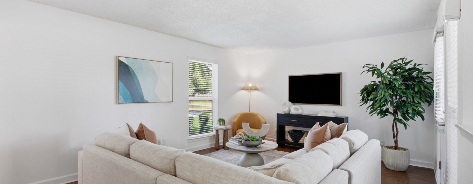 Bright open-concept living room with white sofas, contemporary decor, and floor-to-ceiling windows at Communities of Bent Tree