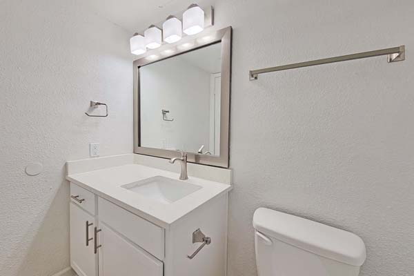 Guest bathroom with custom mirror frame, quartz countertops, refinished cabinetry, and brushed nickle fixtures.